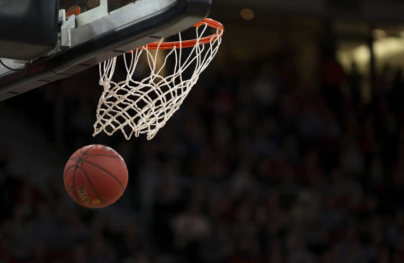 Bola basket melengkung menuju ring di tengah sorak penonton stadion.