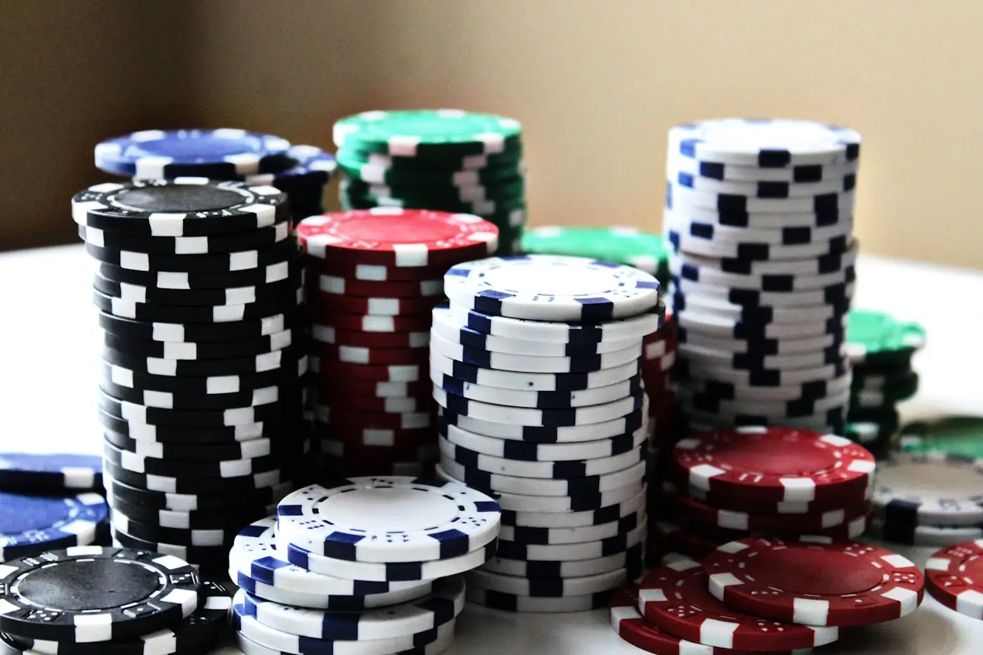Tumpukan chip poker berwarna-warni tersusun rapi di atas meja permainan.